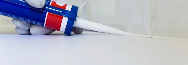 Hand trägt Dichtmittel mit Kartuschenpistole auf